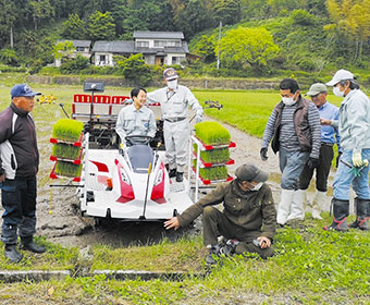 市長が田植え体験しながら米農家と話している様子の写真